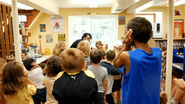 A man shoots a tiny cannon full of water at a crowd of children.